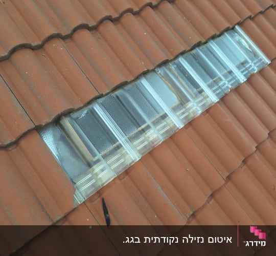 רעפים חומים עם חלון שקוף על הגג